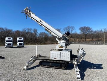Large equipment placed in a open area near two parked trucks