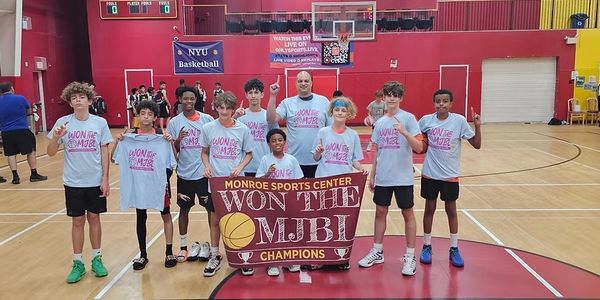 Youth basketball team holding banner celebrating MJBJ championship victory.