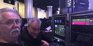 Two men operating video production equipment indoors.