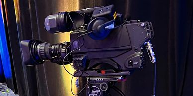 A professional video camera set up on a tripod in a studio.