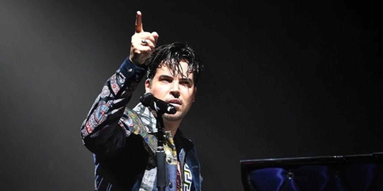 Man passionately performing at a piano on stage under spotlight.