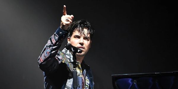 Man passionately performing at a piano on stage under spotlight.