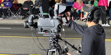 A cameraman filming an event on the street with a professional video camera.