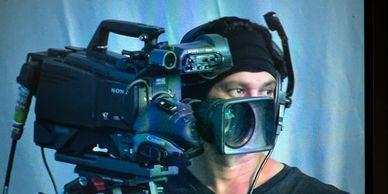 A cameraman filming with a professional video camera indoors.