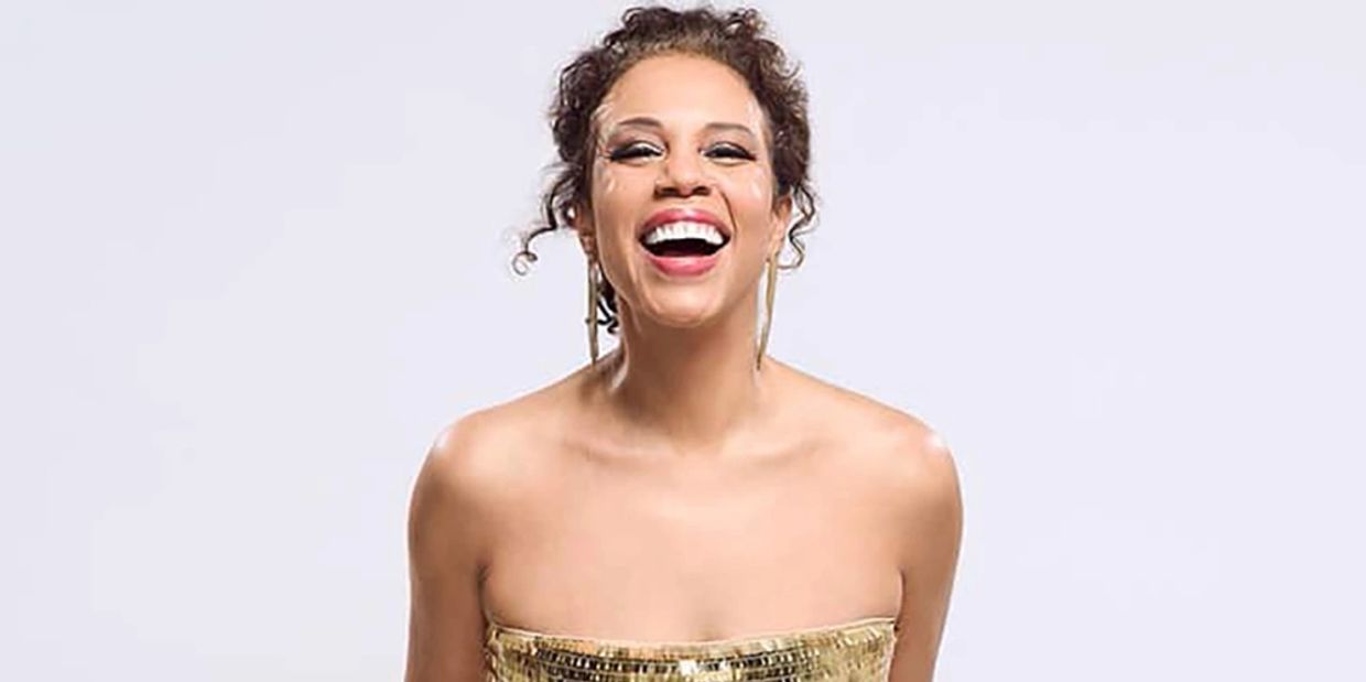A joyful woman in a sparkling gold strapless dress laughing.