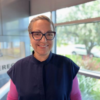 Femme souriante avec lunettes dans un bureau lumineux.