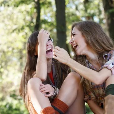 Deux jeunes femmes riant ensemble en plein air.