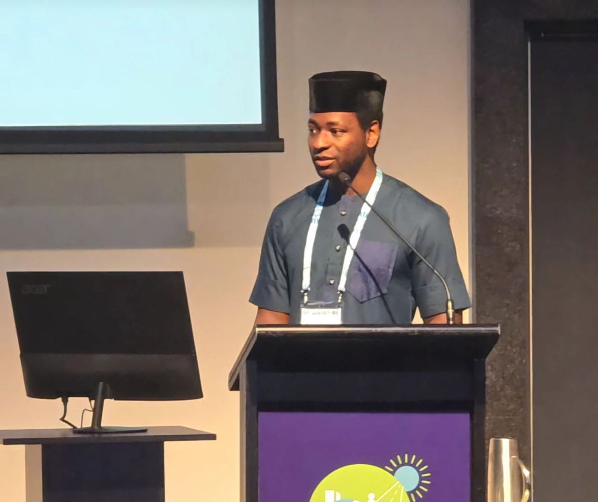 Man in traditional attire speaking at a podium during a conference.