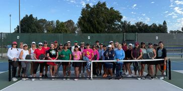 Group of women on a tennis court posing for a photo.