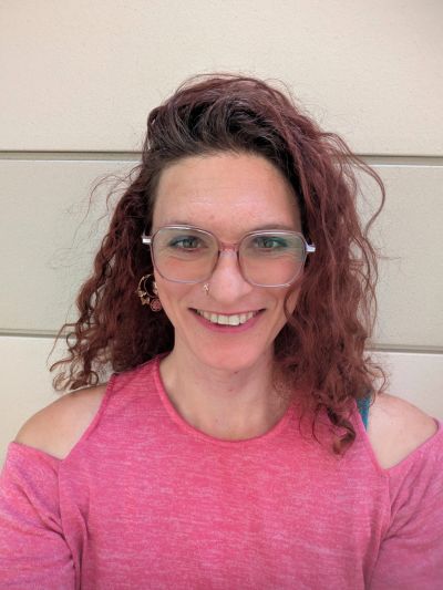 Woman with curly hair and glasses smiling.