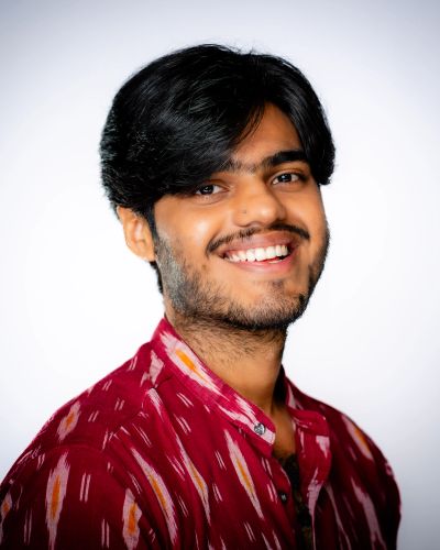 Smiling young man in a patterned red shirt.