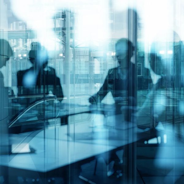 Silhouettes of businesspeople in a glass-walled meeting room.