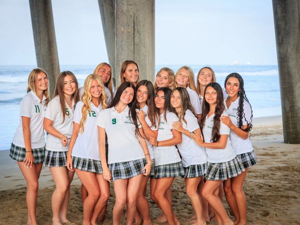Group of girls in school uniforms posing on the beach.