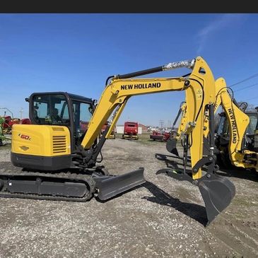 Yellow New Holland excavator on a gravel surface under a clear blue sky.