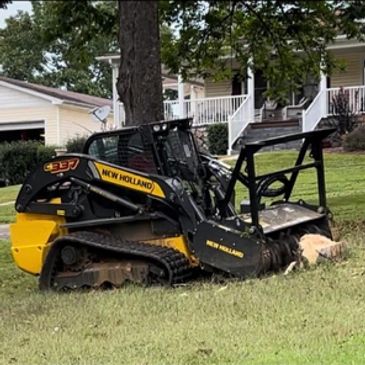 New Holland compact track loader parked on grass in a residential area.