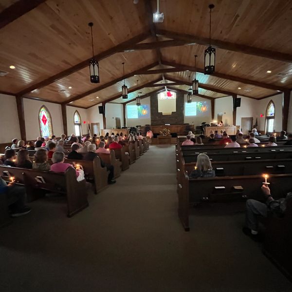 Congregation holding candles during a church service in a wooden chapel.