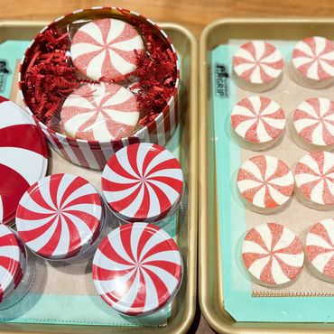 Peppermint-themed cookies and candies displayed on trays and in tins.