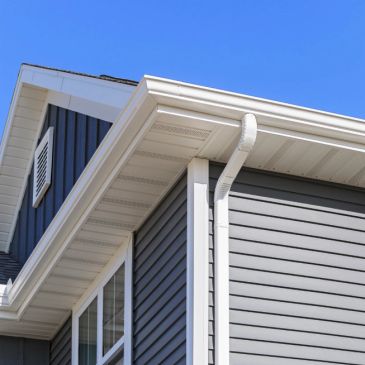 Close-up of a house's roof and siding against a clear sky.