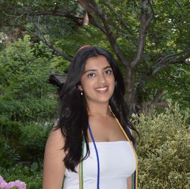 Young woman smiling outdoors in white dress.