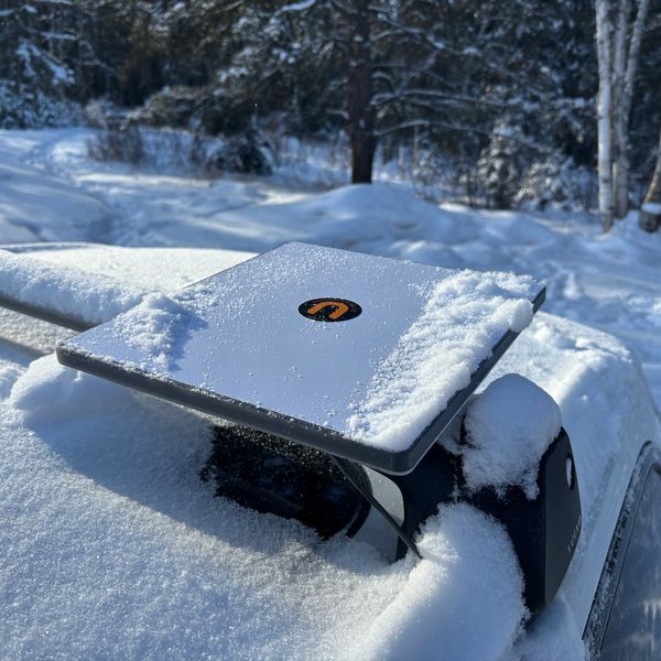 Snow-covered solar panel with a logo outdoors.