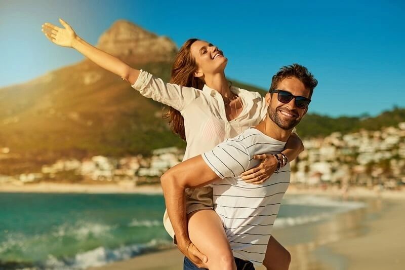 Happy couple enjoying a beach day with a joyful piggyback ride.