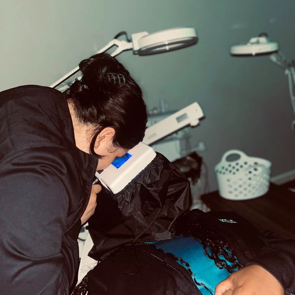 A student in an aesthetics class using a Woods Lamp to inspect a person's skin.