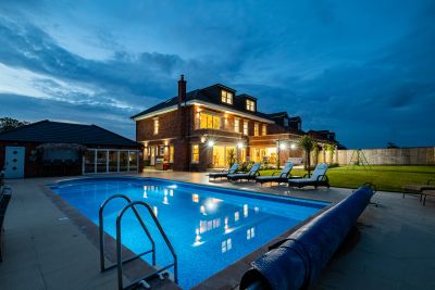Lit house with backyard pool at dusk.