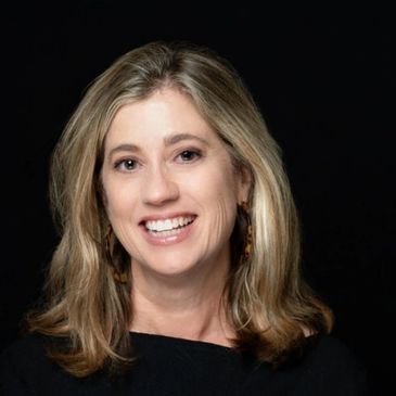 Smiling woman with blond hair against a black background.