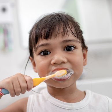 Young girl brushing her teeth, promoting oral health awareness for kids.