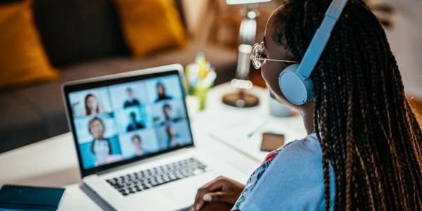 Woman wearing headphones engaging in a virtual meeting on a laptop.