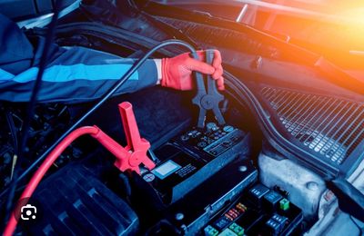 Person using jumper cables to connect a car battery.