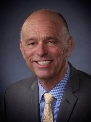 Smiling elderly man in suit and tie.