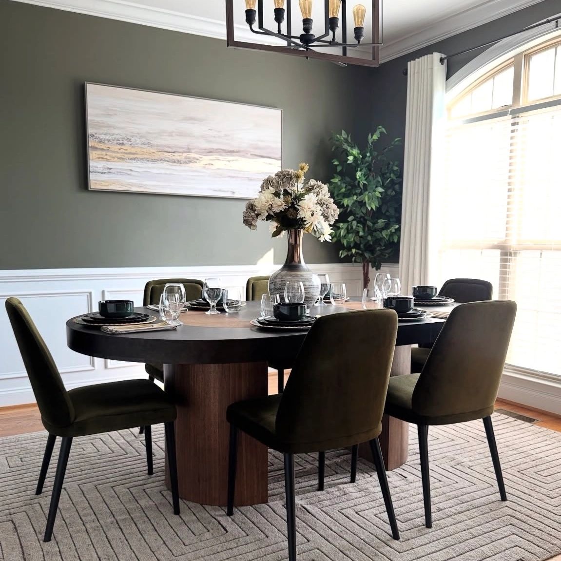 Elegant dining room with round table, green chairs, and large window.