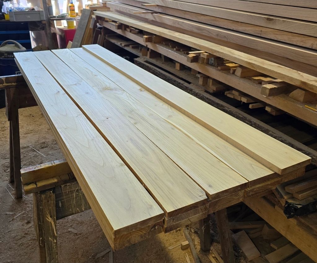 Smooth wooden planks neatly arranged on a woodworking bench.