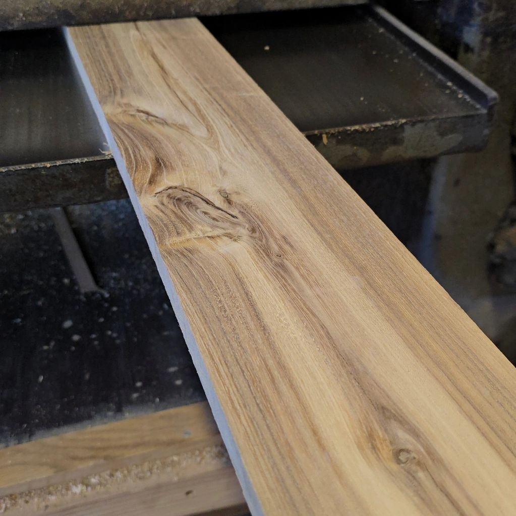 Smooth wooden plank with natural grain patterns on a workbench.