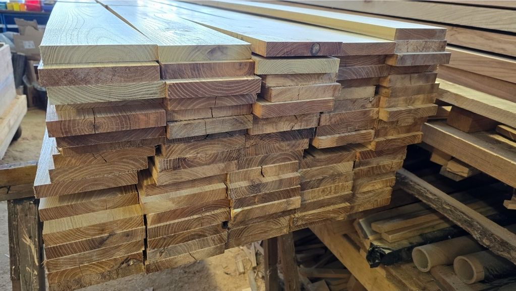 Stack of neatly cut wooden planks in a workshop.
