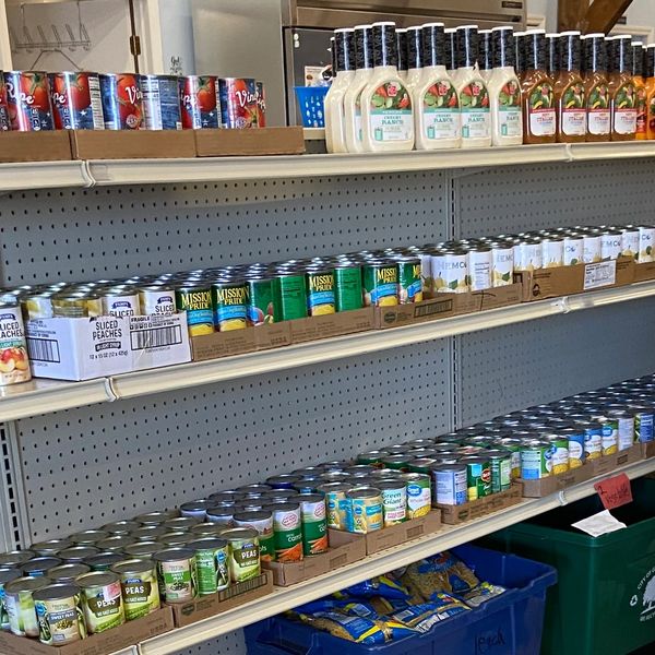 Shelves stocked with canned goods and salad dressings in a store or pantry.