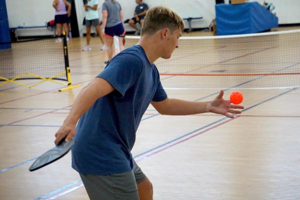 Young man playing pickleball indoors.