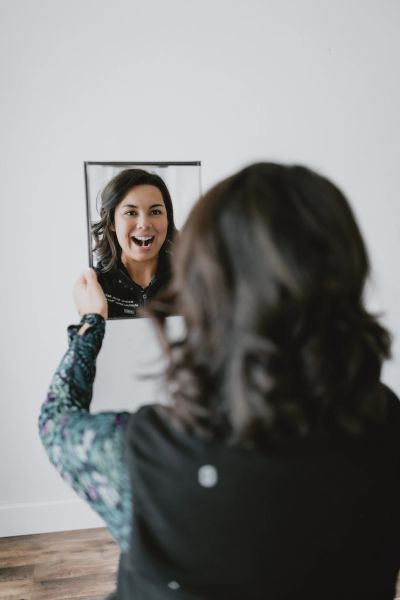 Woman smiling at her reflection in a mirror.