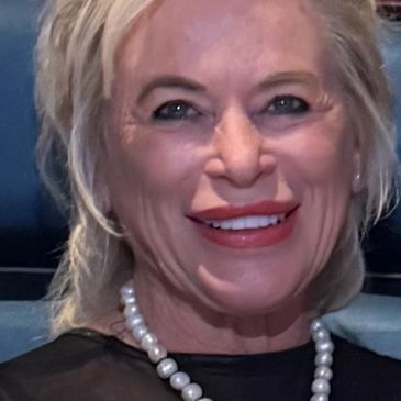 Smiling woman with pearl necklace and blonde hair.