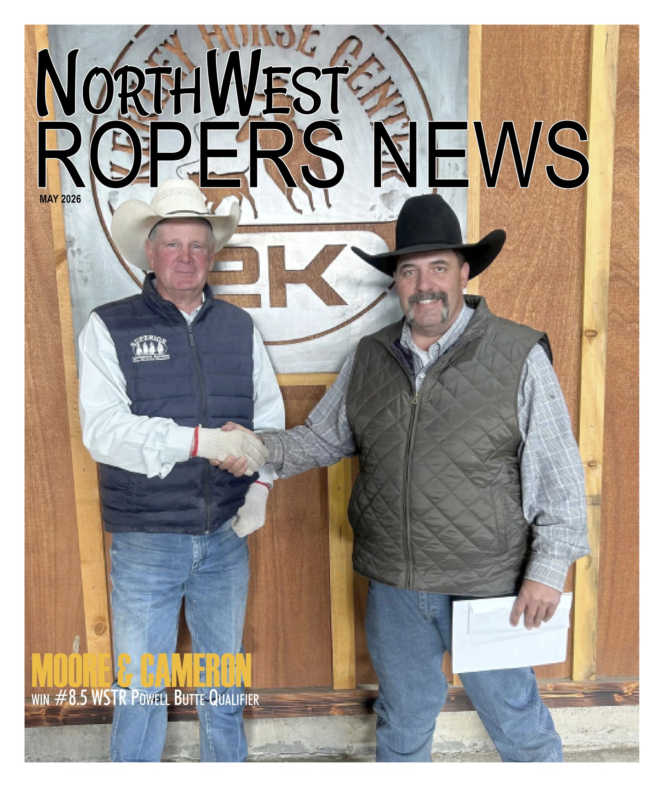 Two men in cowboy hats shaking hands in front of a wooden backdrop at a roping news event.