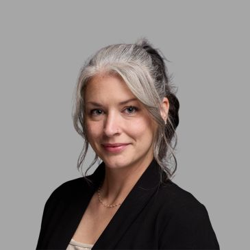 Confident woman with gray hair in a professional headshot.