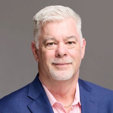 Portrait of a smiling middle-aged man with white hair and beard.