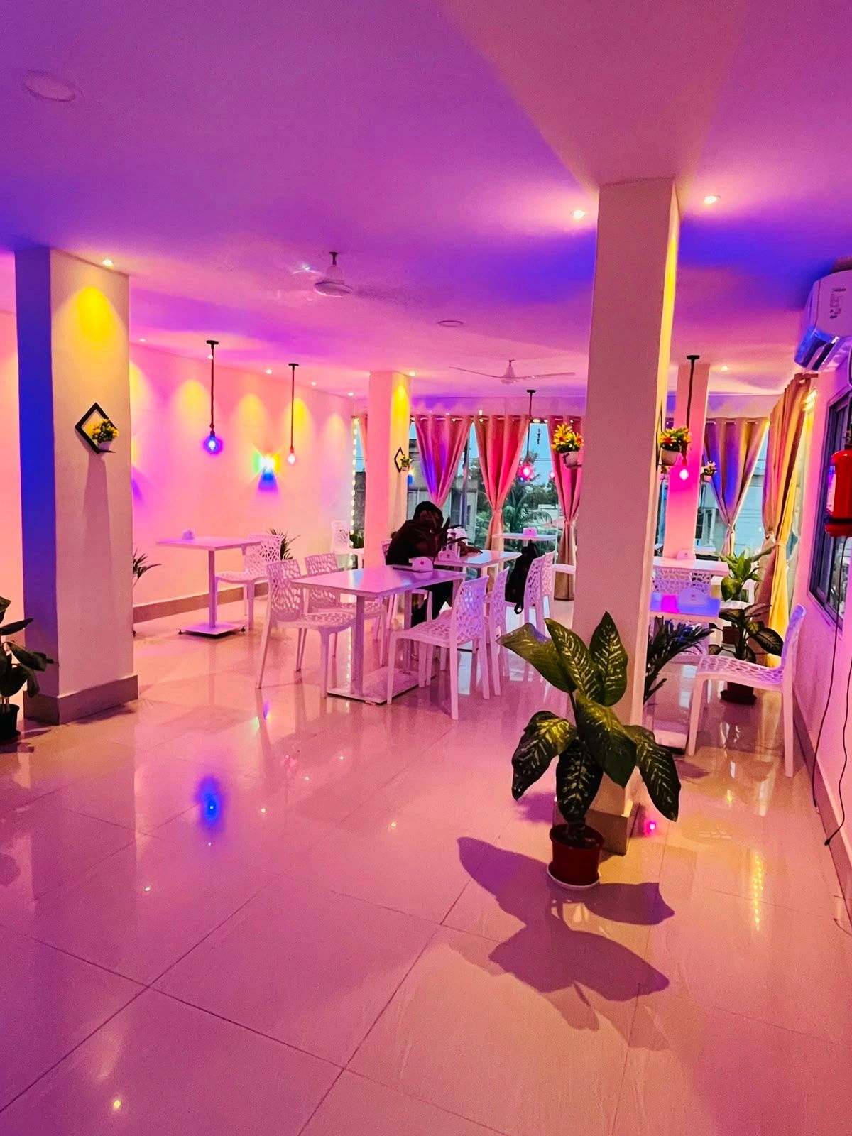 A modern cafe with colorful lighting and white furniture.
