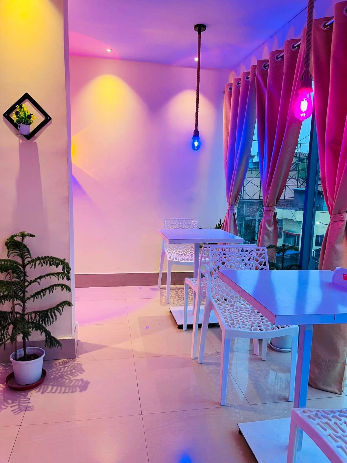 Modern cafe interior with colorful lighting and white furniture.