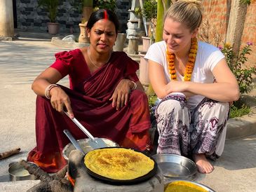 Two women cooking traditional food outdoors.