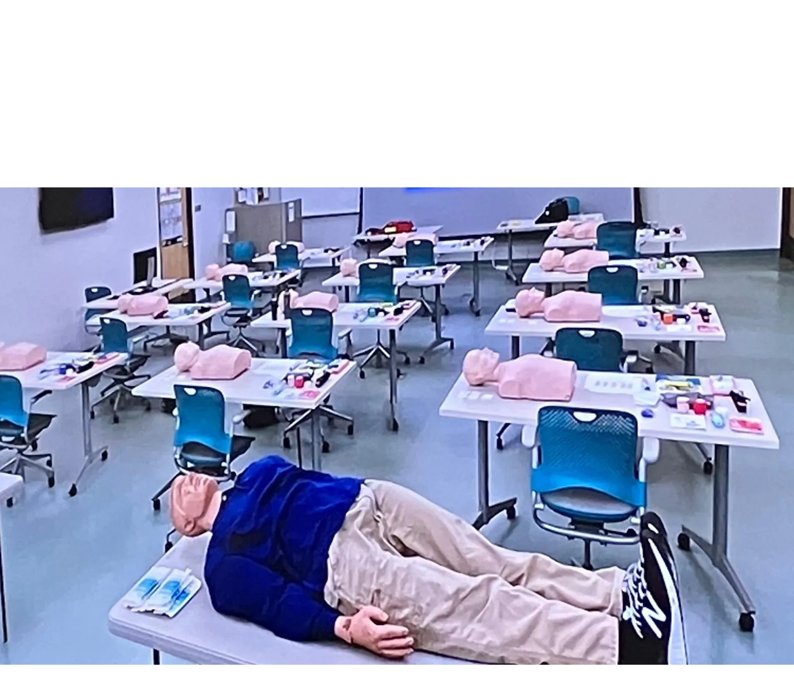 Classroom set up for CPR or first aid training with mannequins on tables.