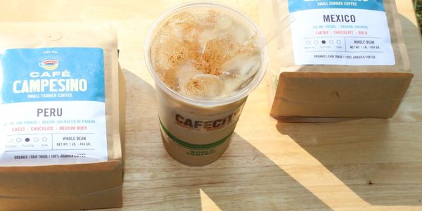 Iced coffee with two bags of Café Campesino coffee beans from Peru and Mexico.