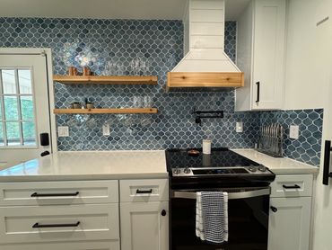 Modern kitchen with blue tile backsplash and white cabinetry.