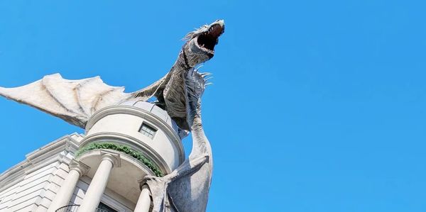 A large dragon statue on a building under clear blue sky.